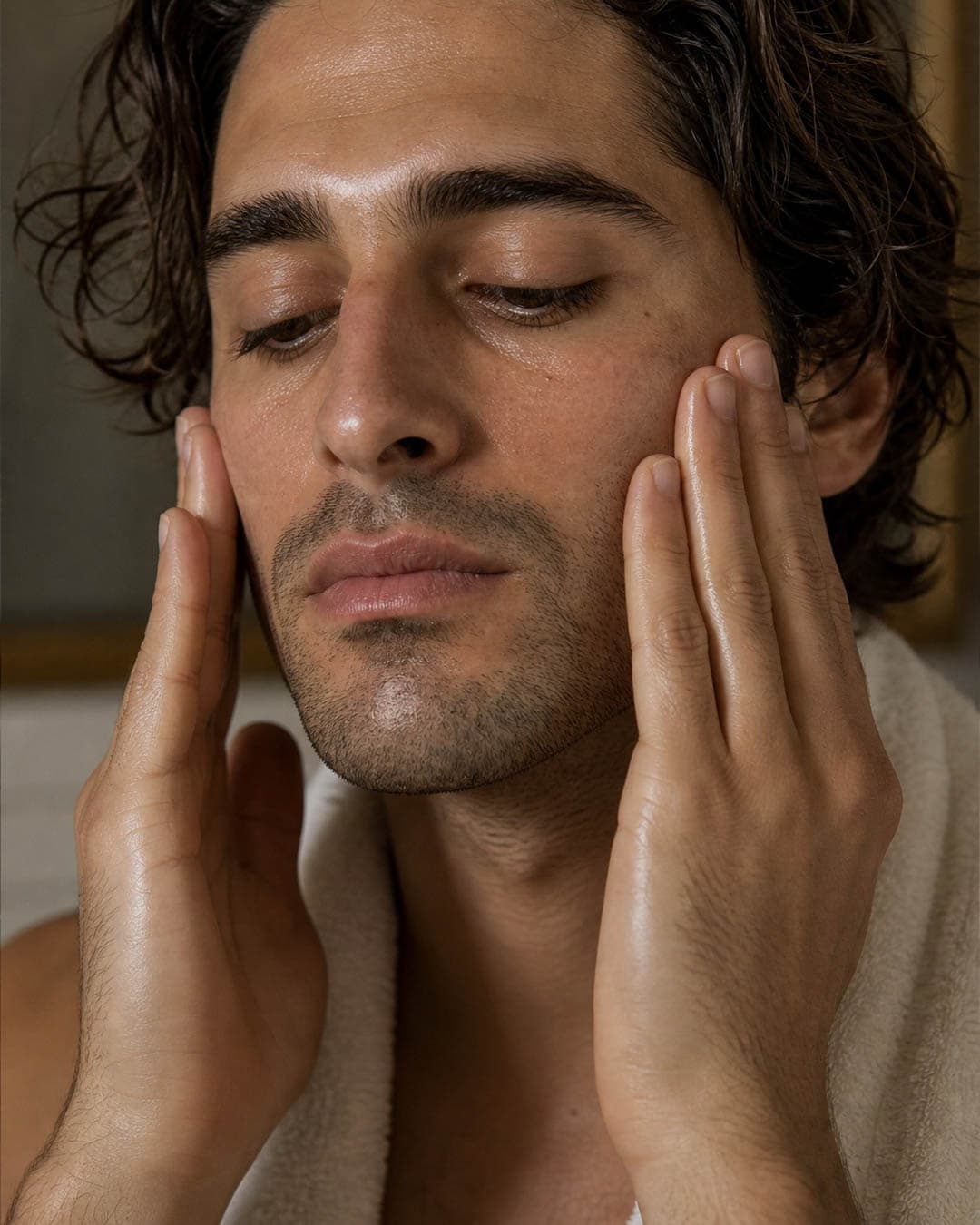 A man pressing oil up both cheeks with both hands